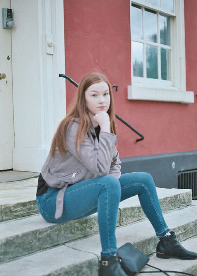 Beautiful young woman sitting outside house