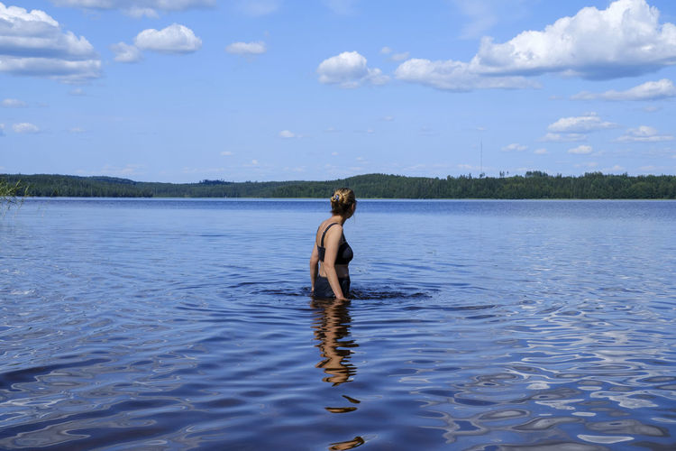 Rear view of shirtless man in lake against sky