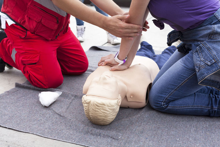 Midsection of instructor teaching paramedic while performing cpr on dummy