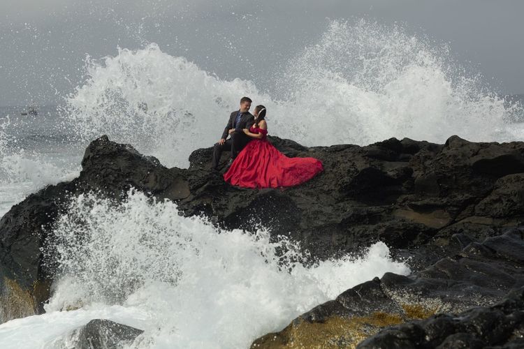Bride and groom with waves splashing on rocks