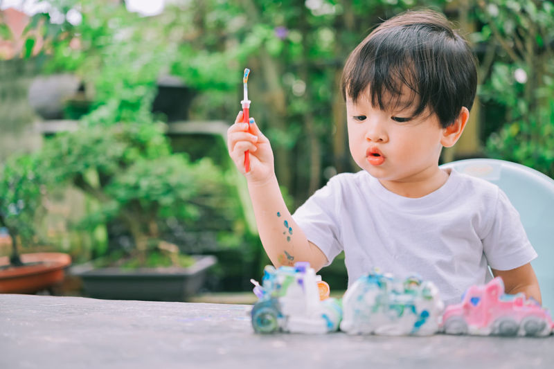 Cute boy holding toy while sitting outdoors