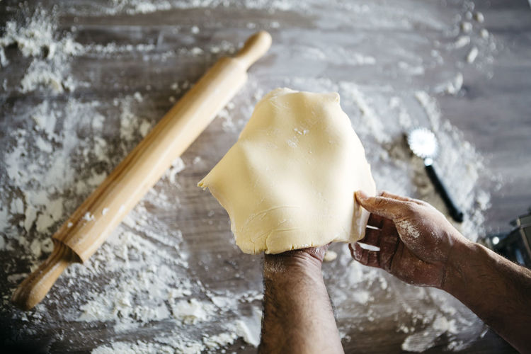 Cropped hands of man preparing dough on table