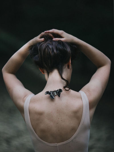 Rear view of woman exercising against black background