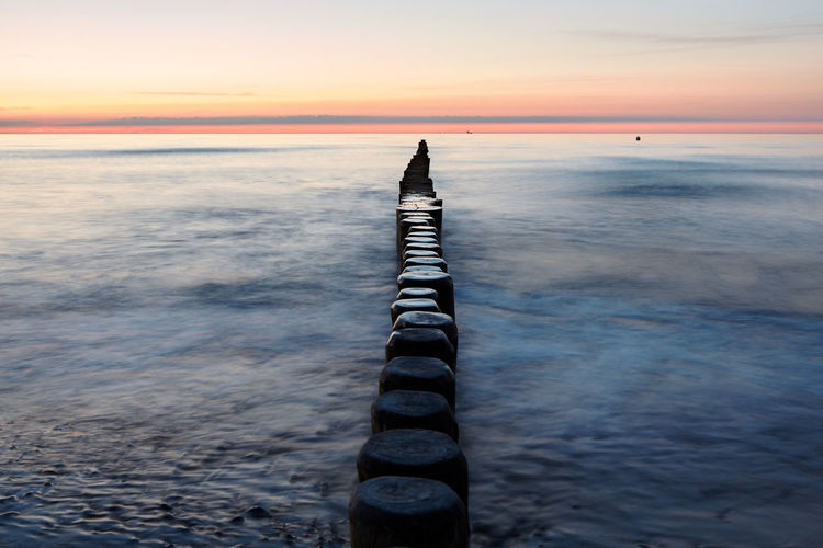 Poles in row at calm sea
