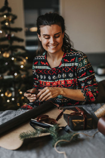 Smiling woman wrapping presents at table