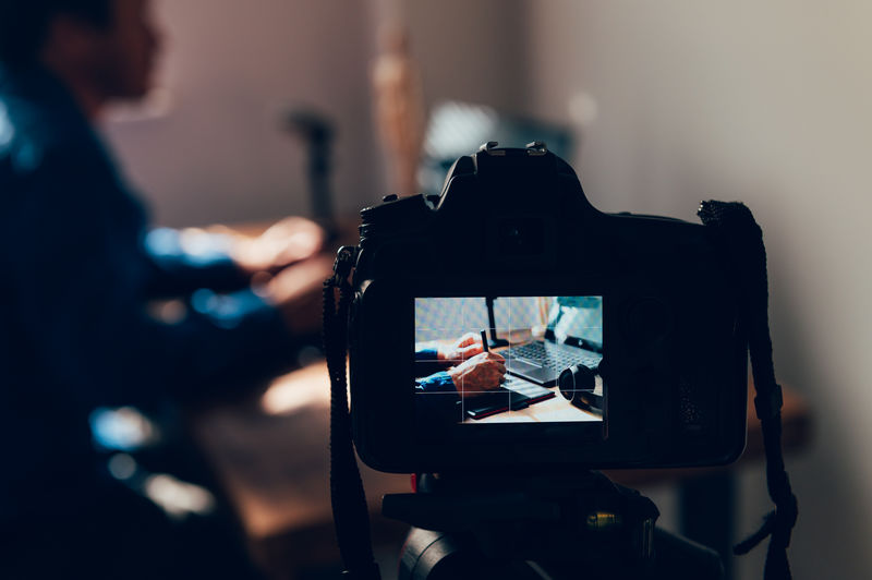 Close-up of camera photographing man working at home