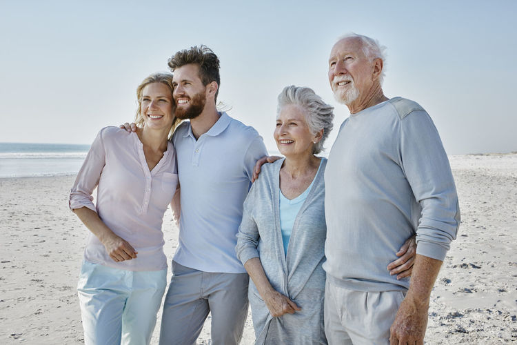 Smiling senior couple with adult children on the beach