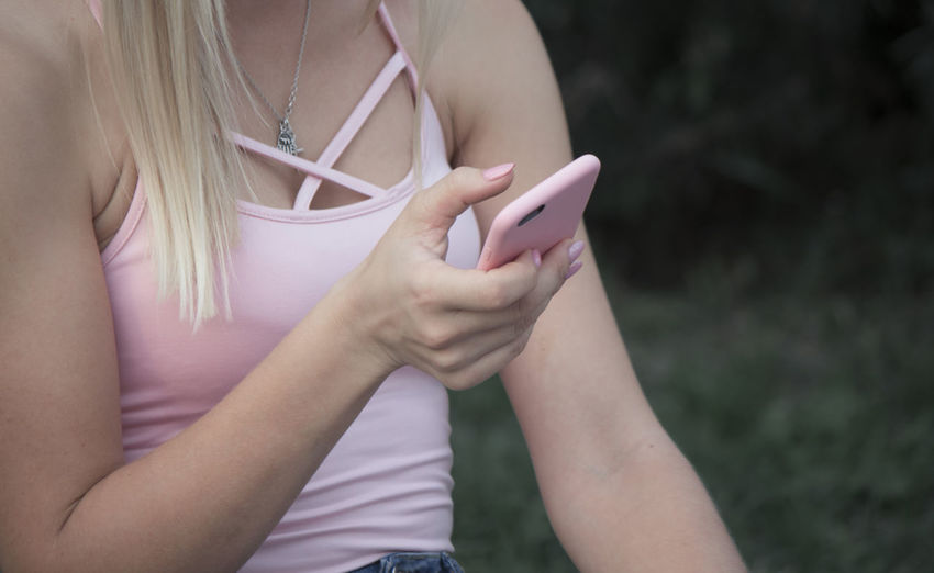 Midsection of woman holding mobile phone outdoors
