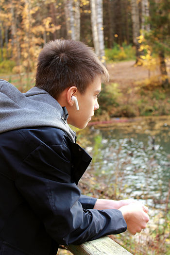 Side view of boy looking at lake in forest