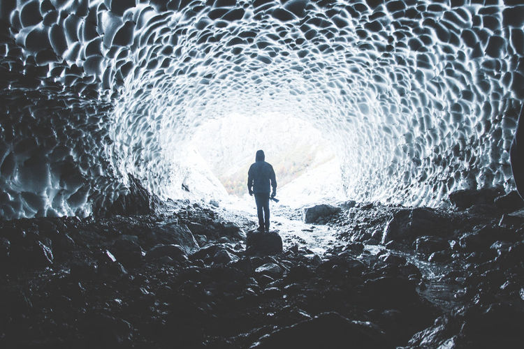 Rear view of silhouette man standing in ice cave