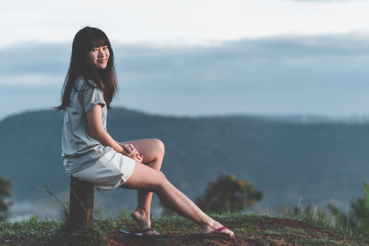 Portrait of young woman sitting on mountain peak