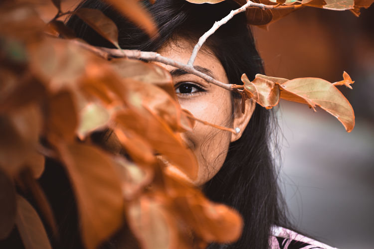 Close-up portrait of young woman with leaves
