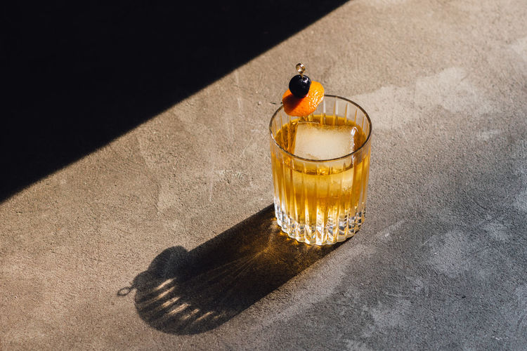 Golden hour whiskey soda highball cocktail with ice, cherry orange peel garnish