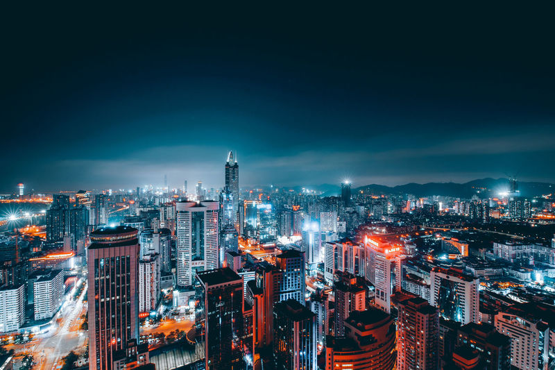 Illumminated buildings in city at night against sky