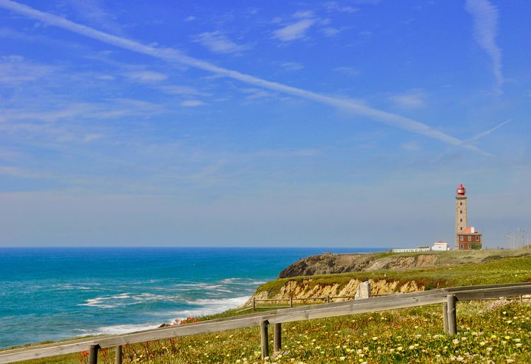 Lighthouse by sea against sky