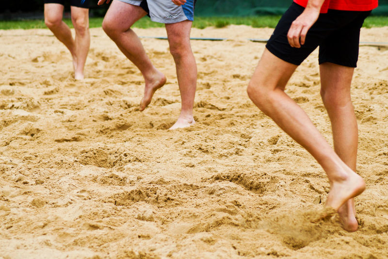 Low section of friends playing on sand