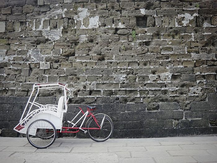 Cycle rickshaw against stone wall