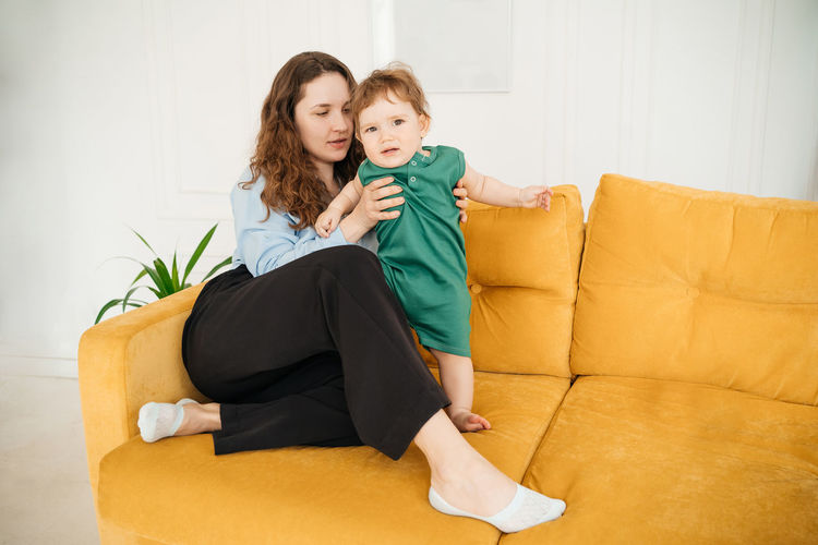 Young mother with a baby son on a yellow sofa