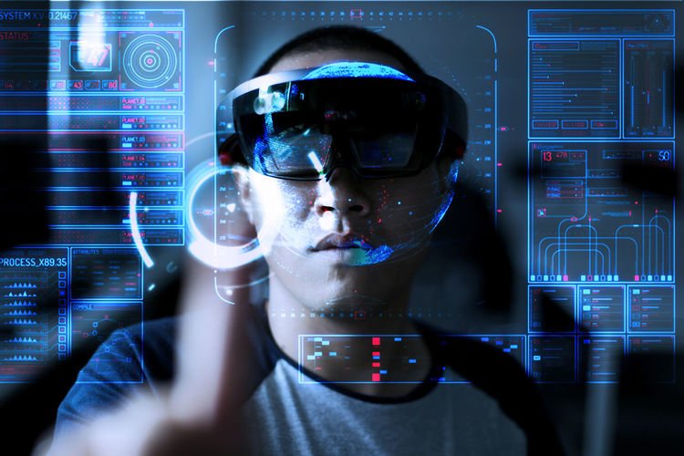 Digital composite image of young man wearing virtual reality simulator while standing with data on invisible screen