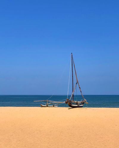 Sailboat on beach against clear blue sky