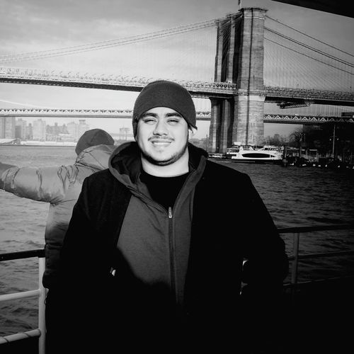 Portrait of smiling man standing against brooklyn bridge