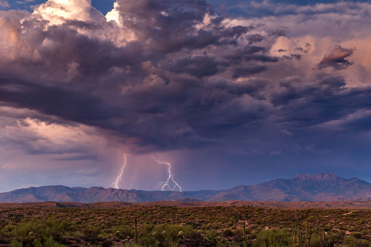 Scenic view of lightning over mountains against cloudy sky