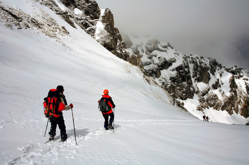 Rear view of men skiing on snowcapped mountain
