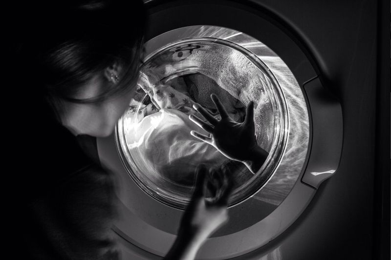 Cropped image of woman looking at hand in washing machine