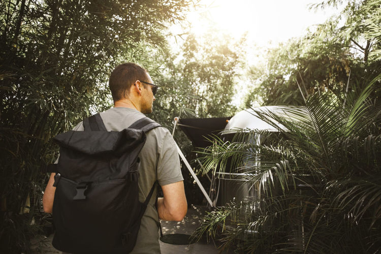 Rear view of man with bag against plants