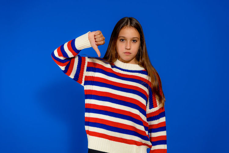 Portrait of teenage girl standing against blue background