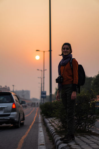 Man standing on road against sky during sunset