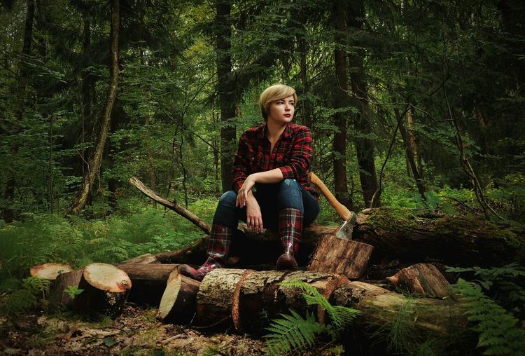Young woman sitting on tree stump in forest