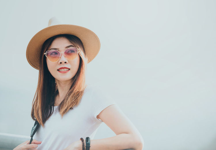 Portrait of young woman wearing sunglasses against clear sky