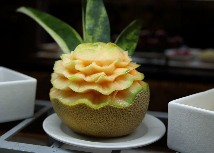 Close-up of carved cantaloupe in plate on table