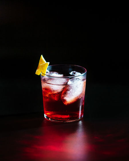 Close-up of negroni cocktail drink in glass against black background