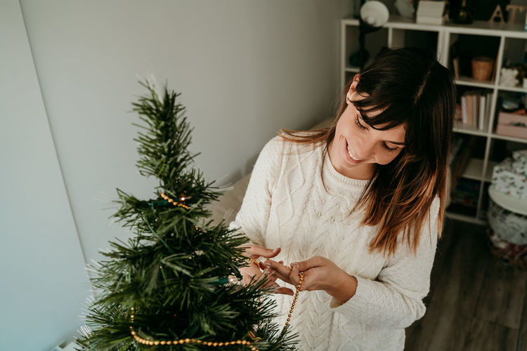 Woman holding christmas tree at home