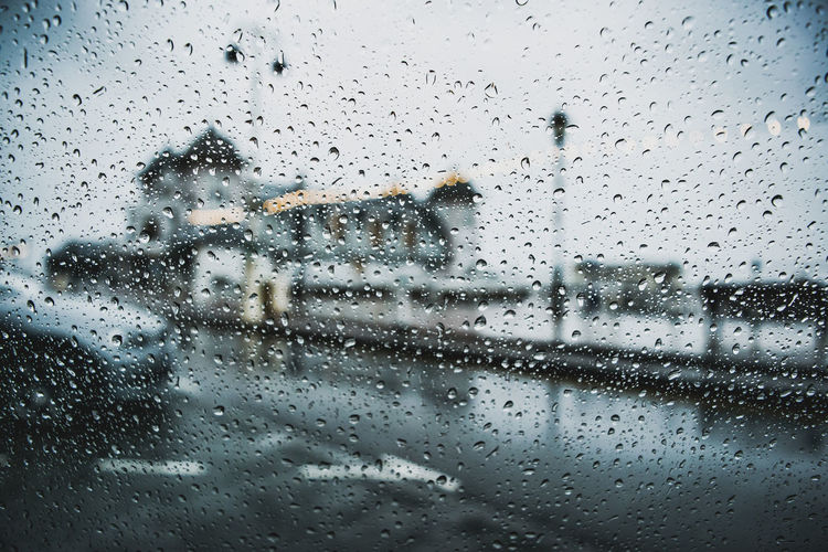Road seen through wet car window during rainy season