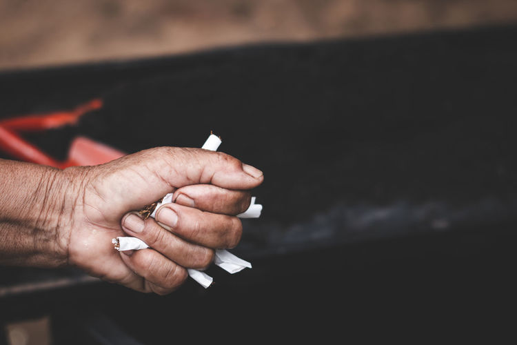 Cropped hand holding cigarettes outdoors