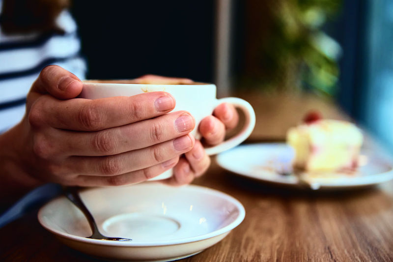 Woman have breakfast at cafe, hold coffee cap in hands