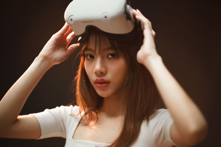 Portrait of young woman wearing hat against black background
