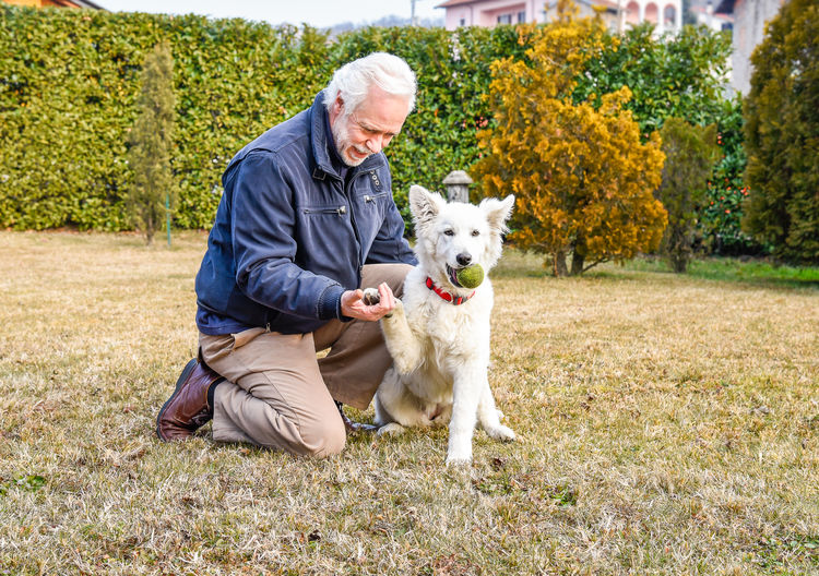 Full length of senior man with dog on grassy field