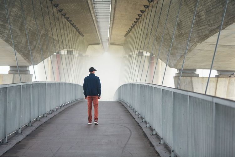 Rear view of young man standing on bridge