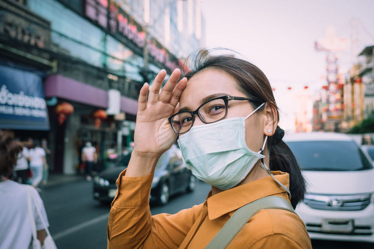 Portrait of woman wearing mask while standing on road