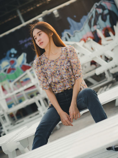 Woman looking away while sitting on bench