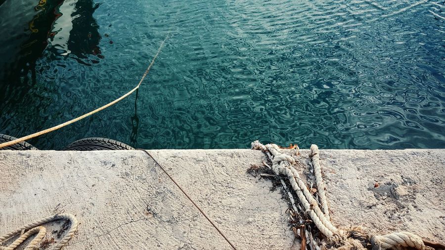 Close-up of wall against blue rippled water