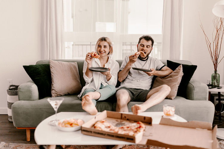 Couple eating pizza while sitting at home