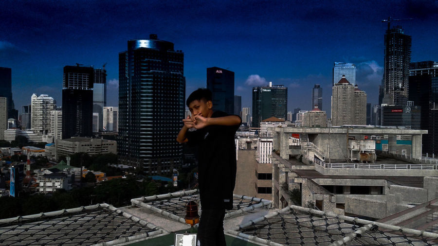 Woman standing by cityscape against clear sky at night