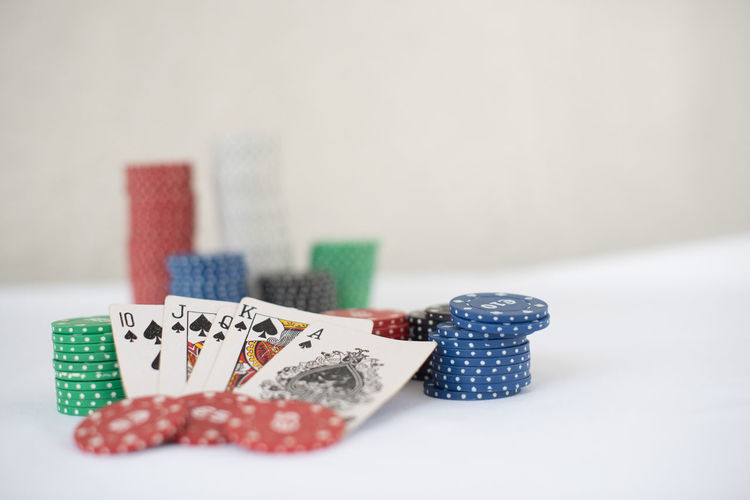 Close-up of cards and chip  on table against white background