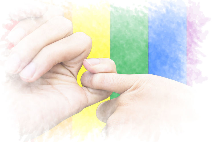 Close-up of people holding pinky fingers multi colored flag