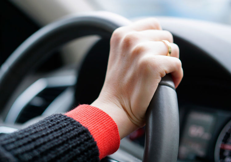 Cropped image of hands on steering wheel at car